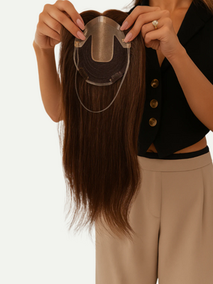 Person holding a hairpiece against a plain background