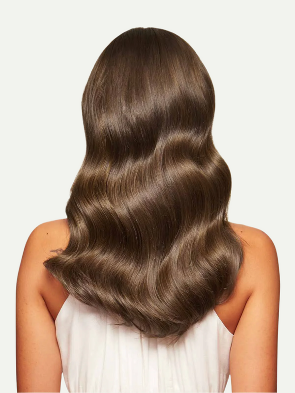 Woman with long, wavy brown hair on a plain background